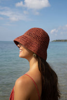 Model in a raffia hat looking up and smiling by the ocean